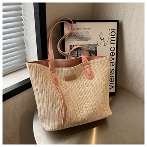 Détail du sac cabas en paille tissée avec garniture en cuir rose et logo