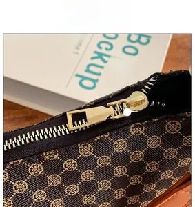 Dettaglio della borsa marrone con stampa floreale dorata e zip in metallo lucido