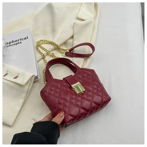 Detail of burgundy quilted leather bag with gold metal clasp and chain strap