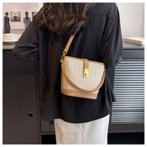 Detail of bohemian woven bucket bag featuring straw texture and golden twist lock closure
