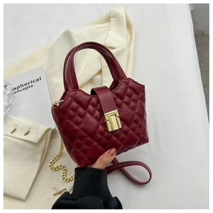Detail of burgundy quilted leather mini handbag with gold metal lock and chain strap