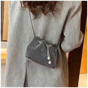 Vue détaillée du sac seau en strass avec chaîne en métal et cordon perlé sur le mannequin