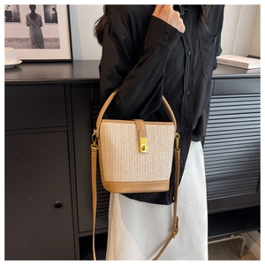 Detail of bohemian straw tote bag showing woven texture and brown leather strap on model