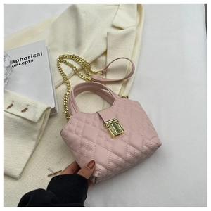 Detail of pink quilted leather handbag with gold metal clasp and chain strap on white blazer