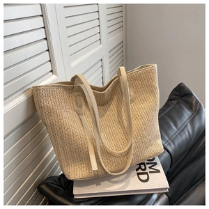 Gros plan détaillé sur le tissage en chevrons et la sangle en cuir du sac cabas beige
