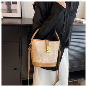 Close-up of woven bucket bag featuring camel leather trim and a golden metal twist-lock