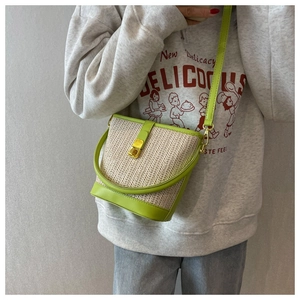 Close-up of neon green leather trim and golden twist lock on a straw bucket bag