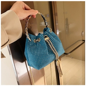 Détail d'un sac seau bleu paon orné de strass brillants avec une poignée en anneau doré