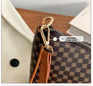 Dettaglio del gancio in metallo dorato e tracolla in pelle della borsa a mezzaluna con logo