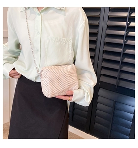 Detail of light pink straw woven crossbody bag with elegant silver chain strap texture