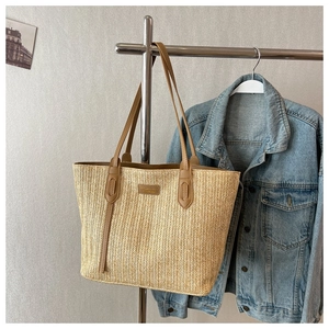Détail du cabas en paille tressée avec lanières en cuir marron et motif en V texturé