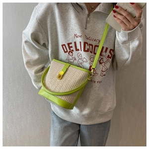 Detail of lime green leather trim and beige woven straw texture on the bucket tote bag
