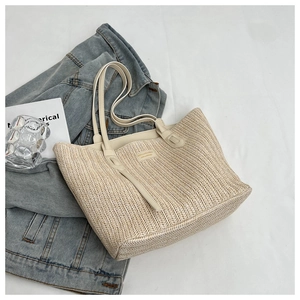 Détail du sac cabas tissé beige montrant la texture à chevrons et l'anse en cuir crème