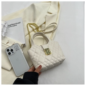 Detailed view of white quilted handbag with golden twist lock and chain strap