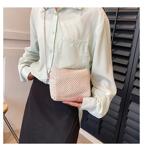 Detailed close-up of beige woven texture crossbody bag with elegant silver chain strap