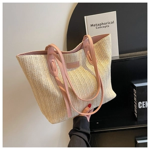 Détail de la texture en paille tressée en V et du logo en cuir rose sur le cabas beige