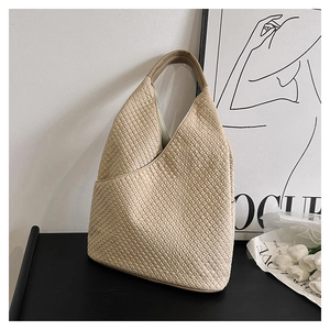 Detailansicht der beigefarbenen Handtasche mit 3D-Karomuster auf schwarzer Oberfläche