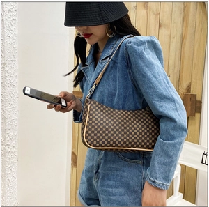 Elegante borsa a mezzaluna con motivo monogram vintage su modella in denim