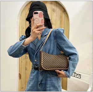 Dettaglio borsa a tracolla a mezzaluna con motivo vintage e zip dorata con outfit in denim