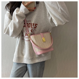 Detail of pink faux leather and straw woven bucket bag with golden metallic clasp