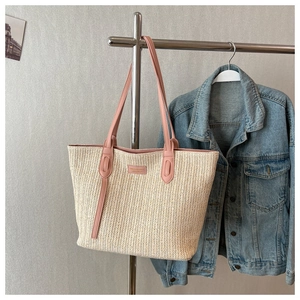 Détail du sac cabas en paille tissée avec anses en cuir rose et texture nette