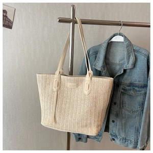 Détail de la texture d'un sac cabas tissé crème avec un petit patch logo sur un cintre