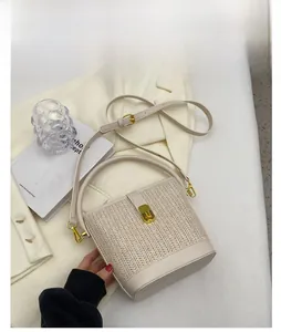 Close-up of white woven bucket bag with smooth leather trim and golden twist lock