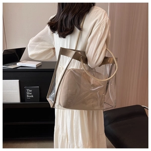 Detail view of transparent PVC tote bag with beige woven handles and inner pouch