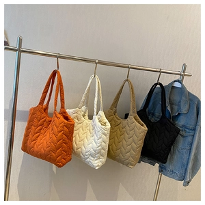 Gesteppte Tragetaschen in Orange, Weiß, Khaki und Schwarz an einem Metallständer