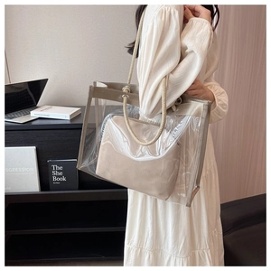 Transparent PVC tote bag with a beige inner pouch and woven rope handle shown on a model
