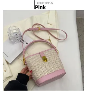 Detail view of pink straw bucket bag with gold twist lock and crossbody strap