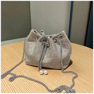 Détail macro du sac seau avec strass argentés, chaîne en métal et cordon perlé