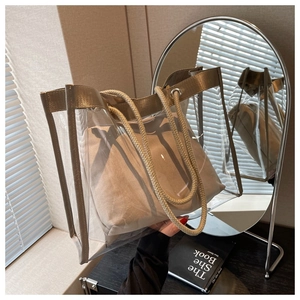 Detail of transparent PVC tote bag featuring gold metallic trim and rope knot handles