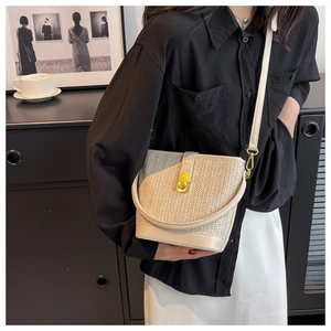 Detail of beige woven bucket bag with fine straw texture and golden metal buckle closure