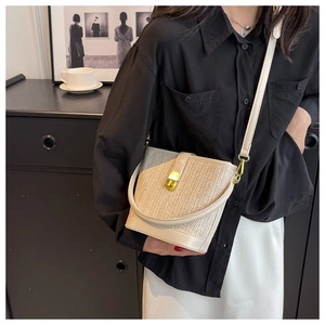 Detail of bohemian straw bucket bag with gold clasp and beige grey woven pattern