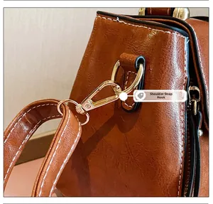 Dettaglio del gancio dorato e tracolla rimovibile sulla borsa in pelle cerata marrone