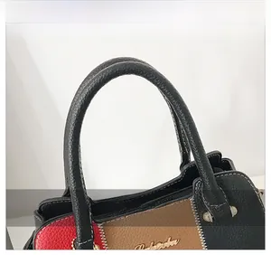 Détail des coutures contrastées sur sac en cuir avec logo doré et poignée grainée
