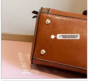 Dettaglio dei rivetti dorati resistenti all'usura sulla borsa in pelle cerata marrone