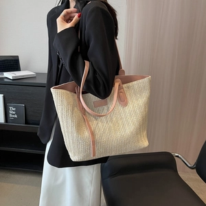 Grand sac cabas en paille tressée beige avec lanières en cuir rose porté par un mannequin