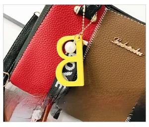 Détail du sac en cuir bicolore avec pendentif B jaune et accent de perle