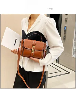 Dettaglio di una borsa marrone in pelle cerata con finiture dorate e cerniere decorative