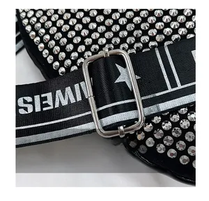 Gros plan sur la boucle métallique réglable d'un sac en strass avec bandoulière tissée