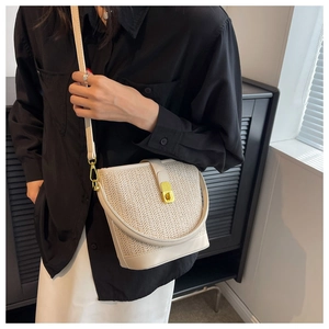 Close-up of cream woven straw bucket bag with gold hardware and V-pattern texture