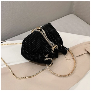Gros plan détaillé d'un sac seau noir en strass avec poignées dorées et bandoulière chaîne