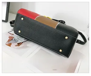Vue détaillée du fond de sac bicolore avec clous dorés et texture en cuir grainé fin
