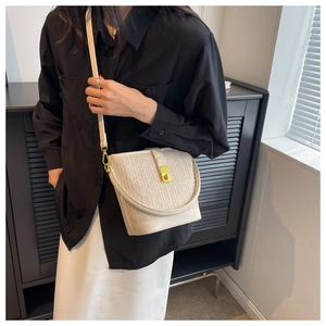 Detail of bohemian straw bucket bag with gold clasp and smooth leather trim