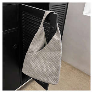 Detailaufnahme der hellgrauen Hobo-Tasche mit geprägter Blasenstruktur auf schwarzer Tür