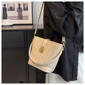 Detail of bohemian woven bucket bag with metallic gold twist lock and PU leather strap