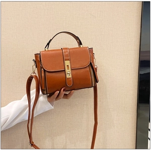 Borsa in pelle cerata marrone con chiusura dorata e dettagli di cerniere laterali