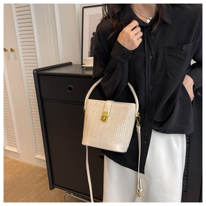 Detailed view of bohemian straw bucket bag with gold metal buckle and woven V-pattern